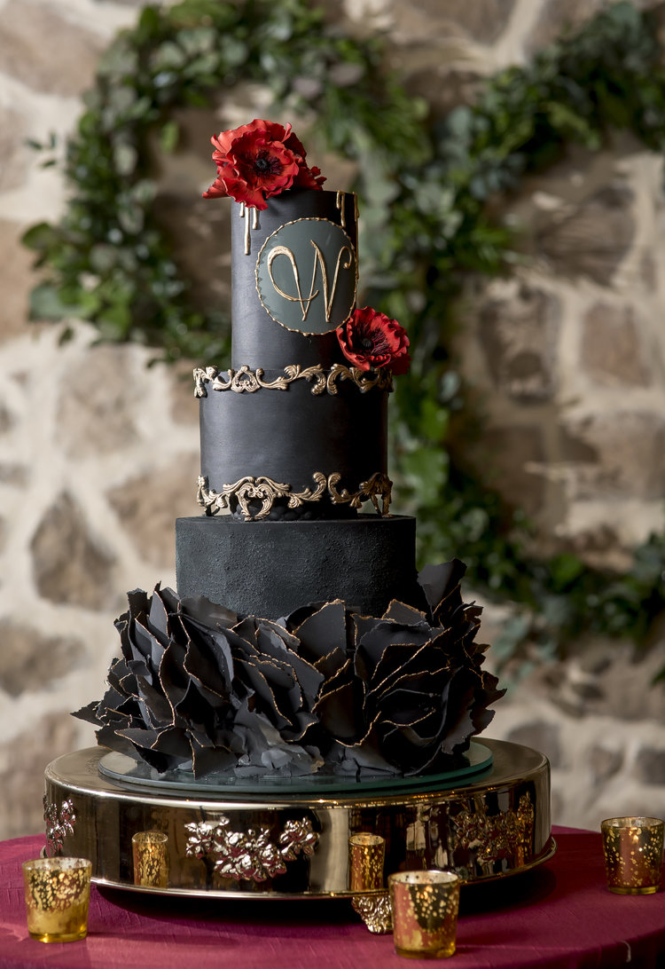 Three tiered cake with black icing and red flowers