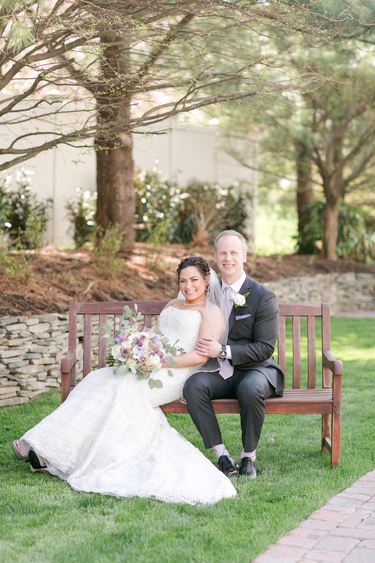 Bride and groom sitting on wooden bench outside